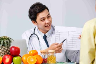 Smiling Asian Male Dietician Showing Chart Patient While Explaining Solution Heathy Diet White Background 11Zon